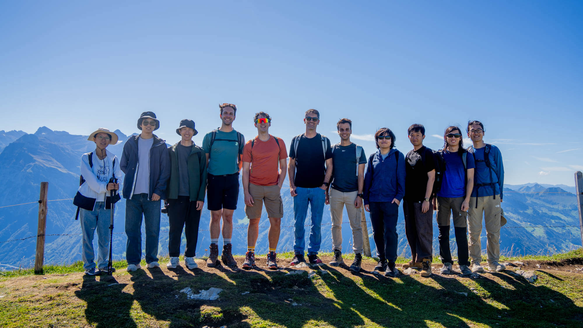 The lab team standing together on a mountain ridge on a sunny day