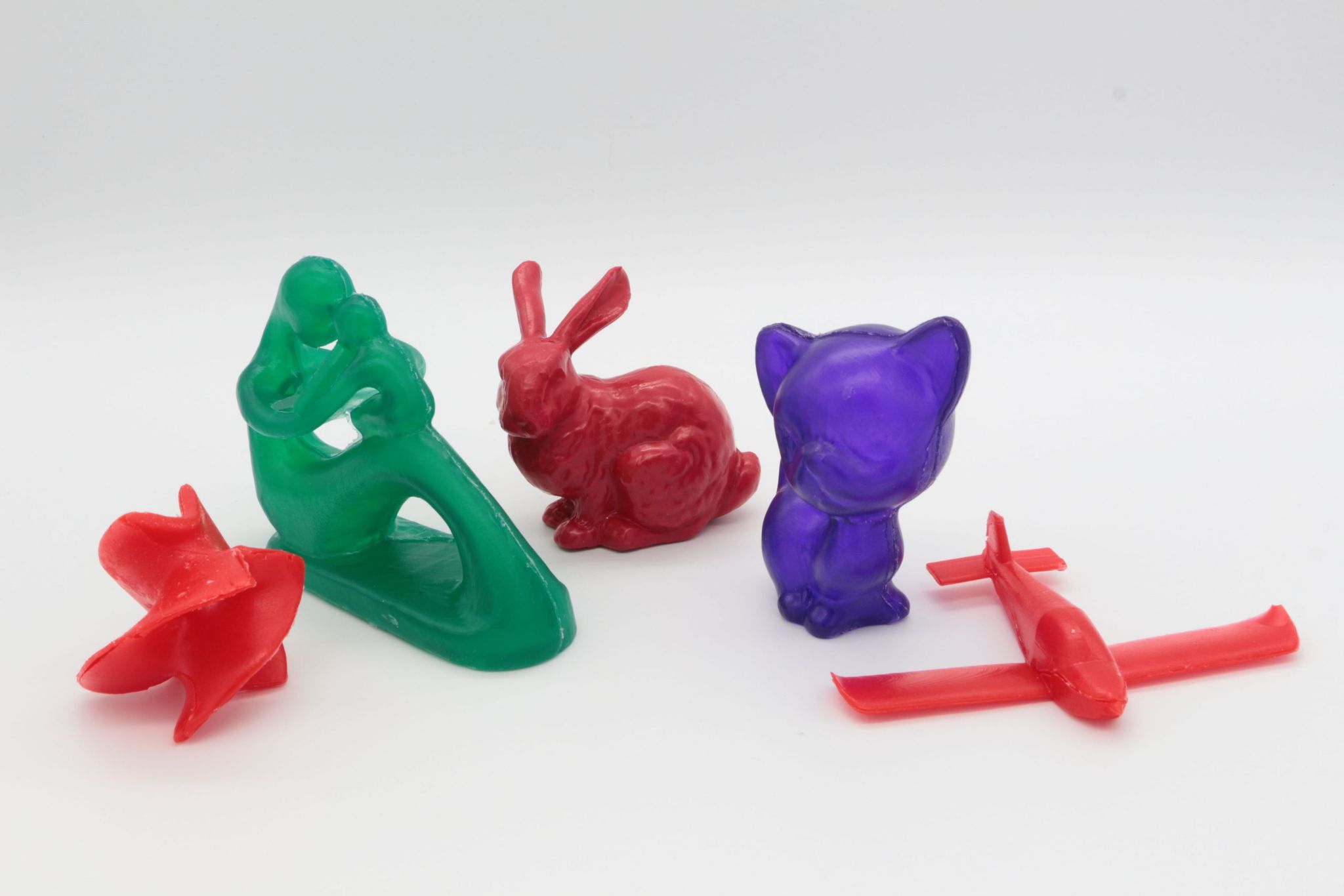 Cast objects in red, green and purple resin, including a bunny and a cat