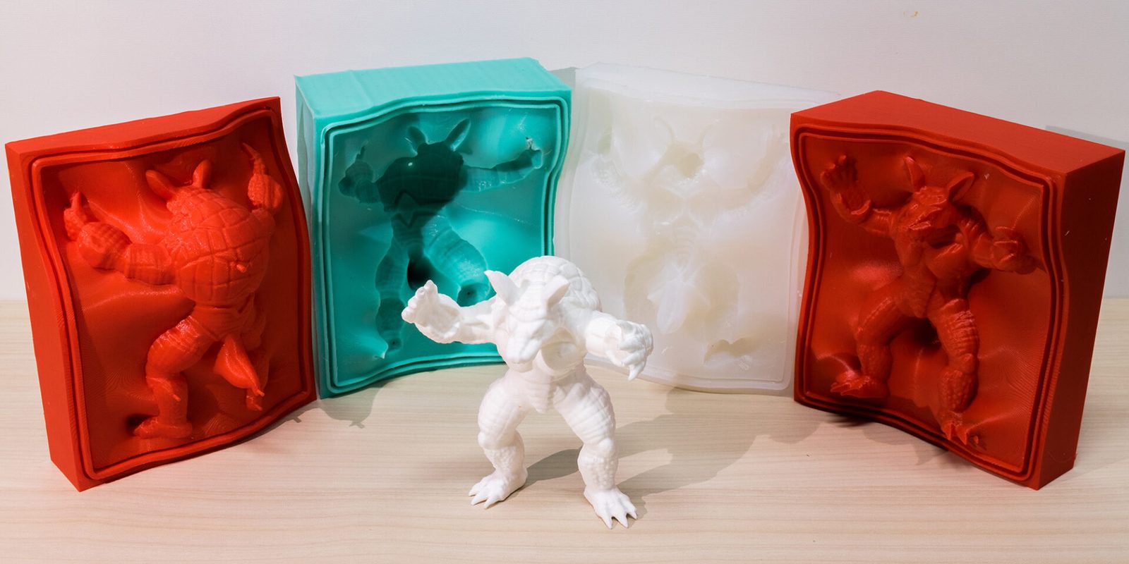 Red and teal silicone moulds beside the white figure cast from them